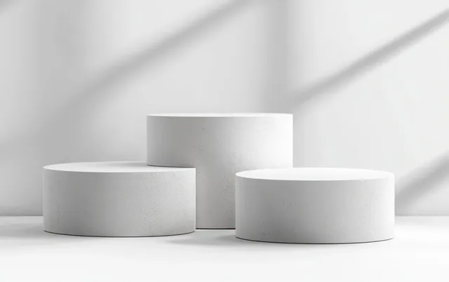 Three empty white cylindrical podiums of varying heights arranged on a bright white background with soft shadows.