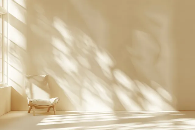 Beige wall and floor in warm sunlight with window and foliage shadows forming delicate striped patterns.