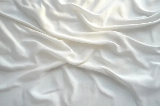 White wrinkled fabric draped background with soft natural light shadows and calm texture