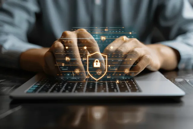 Hands typing on laptop with glowing cybersecurity shield interface with Data Privacy