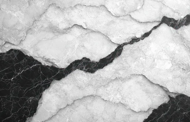 Close-up of a white marble surface with bold black veins forming crack-like abstract patterns.