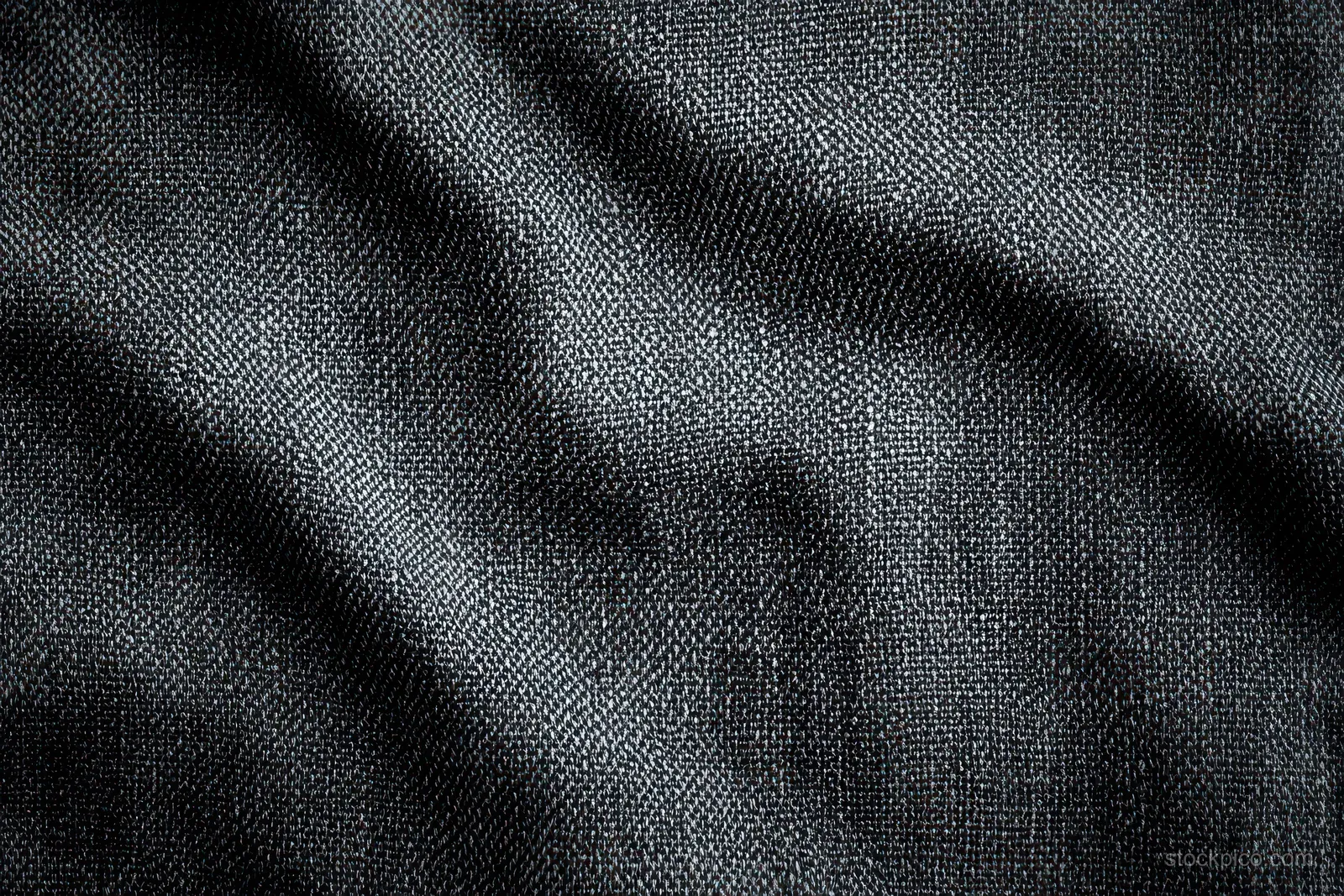 Close-up of dark woven fabric with visible thread texture, gentle folds, and soft shadows.
