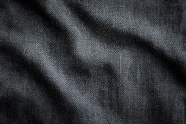 Close-up of dark woven fabric texture with thread pattern and soft highlights