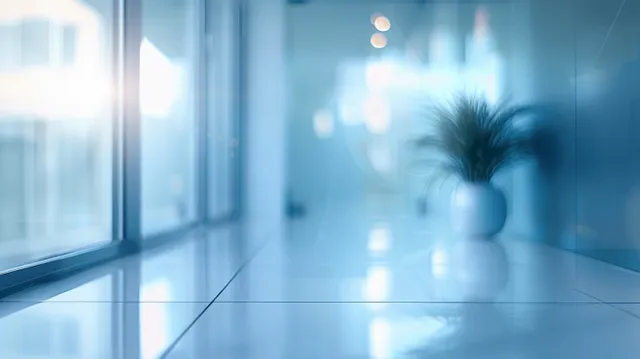 Minimal office corridor with glass windows and soft blue daylight reflections along the floor.