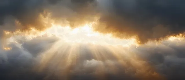 Sun rays pierce layered storm clouds, creating dramatic golden light over a dark sky