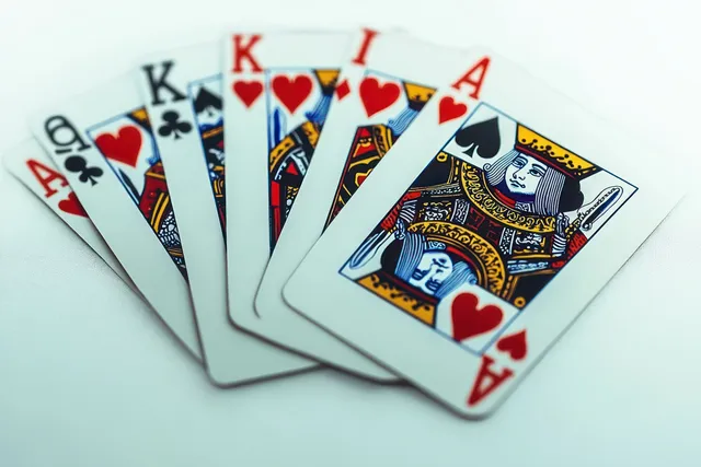 A fan of playing cards with aces, kings, and queens showing hearts, spades, and clubs on a white background.
