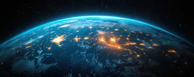 View of Earth from space at night with bright city lights across South America and dark ocean around the continent.