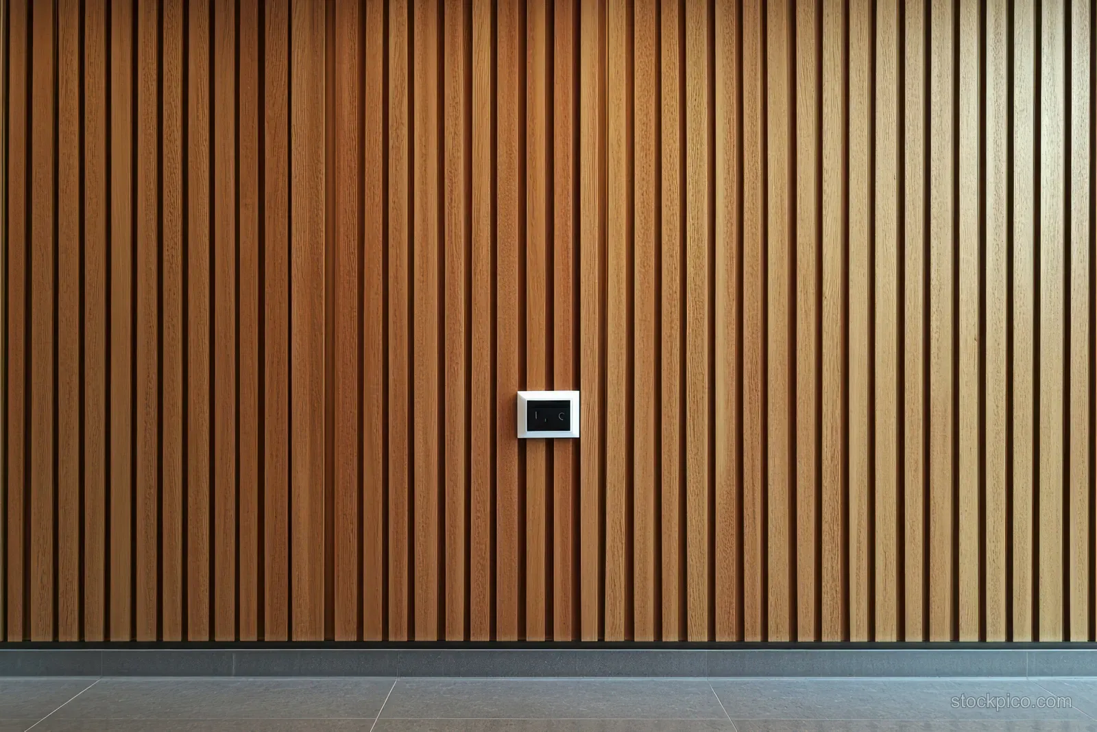 Centered power outlet on a vertical wooden slat wall above a gray tiled floor.