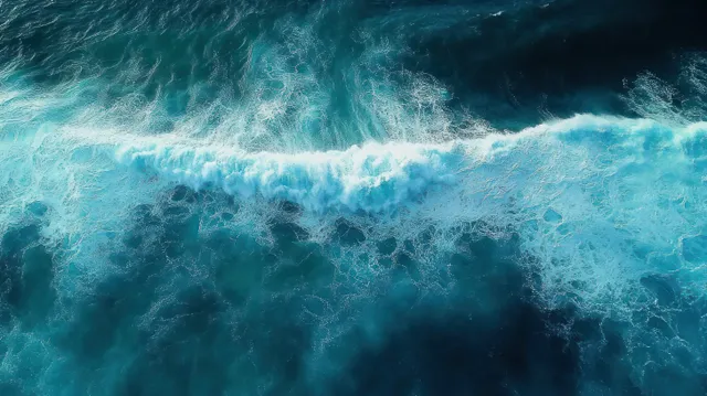 Aerial ocean wave crests breaking over deep blue water with bright turquoise foam patterns