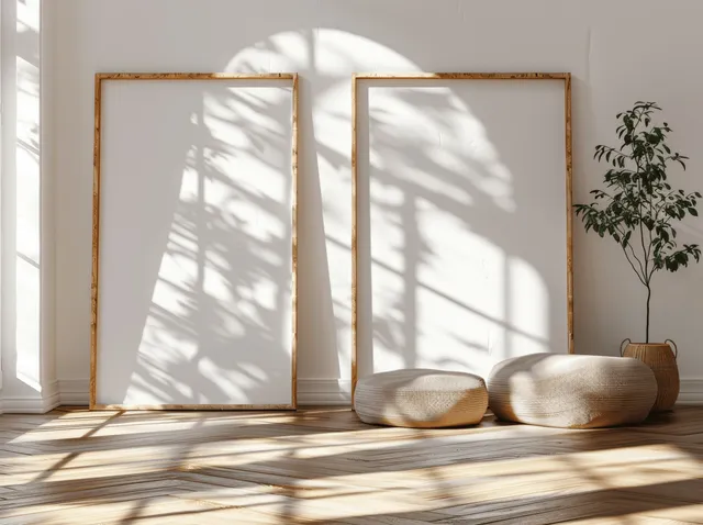 Two blank wooden frames lean on a white wall while window shadows stretch across a parquet floor.