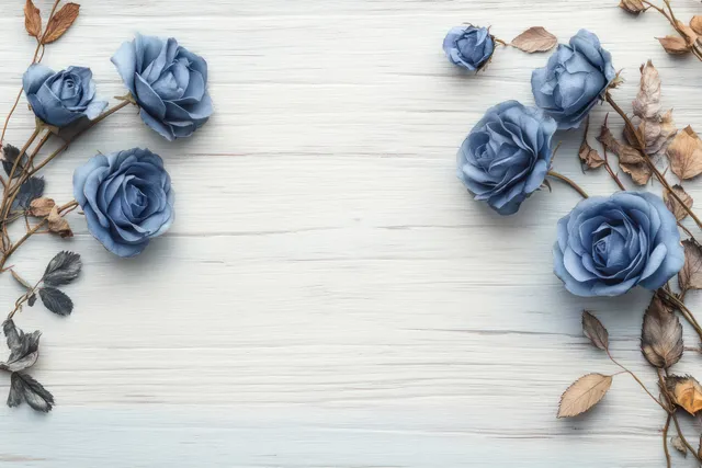 Blue roses and dried brown leaves arranged on white wooden planks in calm still life