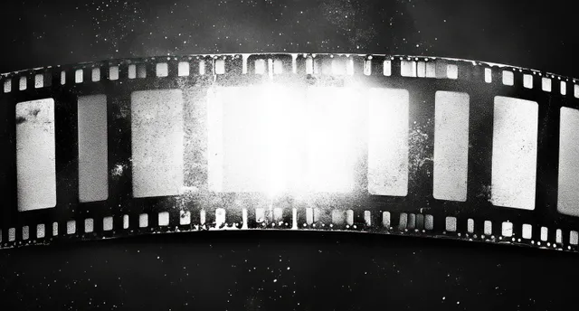 Tira de película negra con efecto grunge, fotogramas negativos desvaídos y polvo flotando sobre un fondo cinematográfico oscuro.