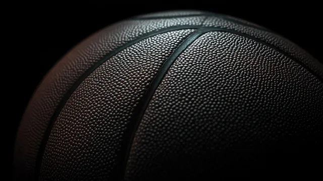Close-up basketball texture with pebbled grip and deep black grooves under focused lighting