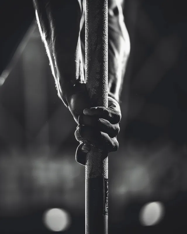 Pole vaulter’s gloved hands grip the pole tightly under stadium lights