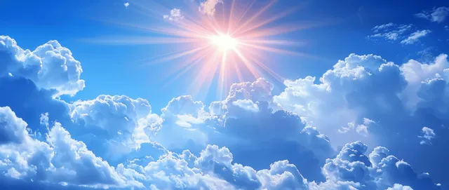 Sun shines through bright white clouds in a vivid blue summer sky with visible sun rays.