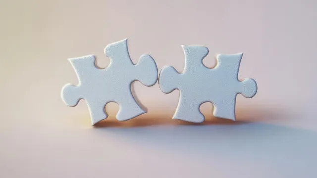 White puzzle pieces interlock on a soft pastel background with gentle shadowing.