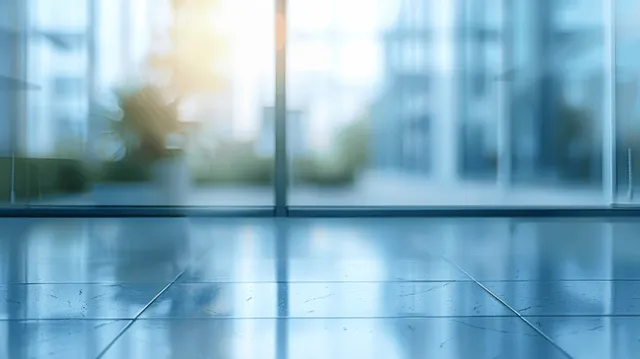 Empty modern office floor with glass reflections and soft city light through windows