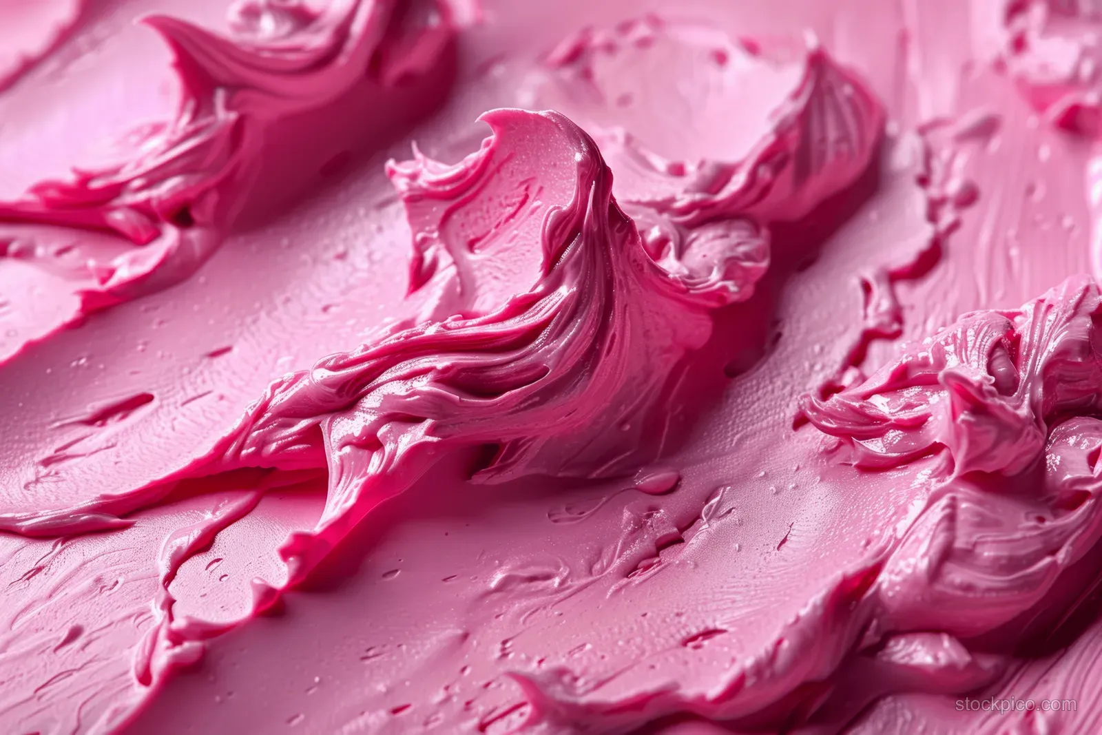 Pink clay mask paste spread in glossy streaks with visible creamy texture close to the surface.