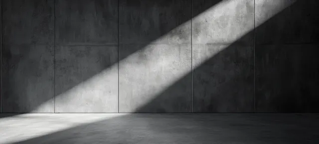 Minimalist concrete room with harsh spotlight shadows across empty studio floor
