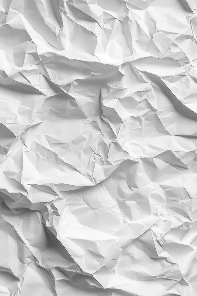 Close-up of crumpled white paper with detailed folds and creases casting distinct shadows across a textured surface.