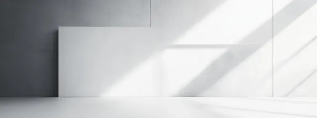 Blank white rectangular panel leaning against a concrete wall in a bright room with diagonal daylight shadows.