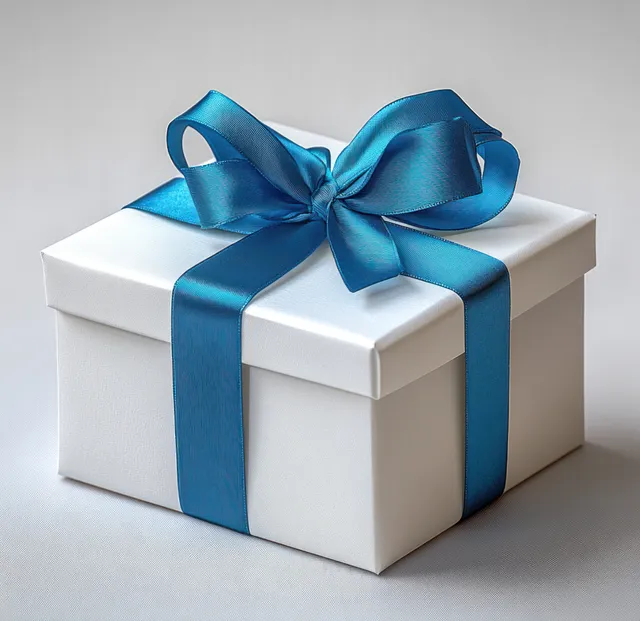 White square gift box wrapped with shiny blue satin ribbon tied into a large bow on a light surface.