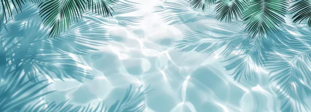 Palm leaf shadows stretch over rippled water under bright daylight with light blue and white tones.