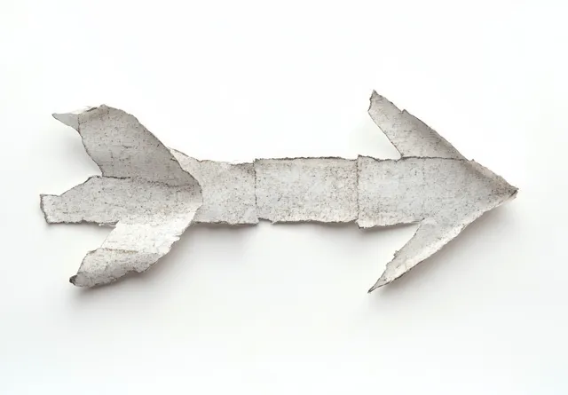 Torn weathered white paper forms a rightward arrow shape on a plain white background.