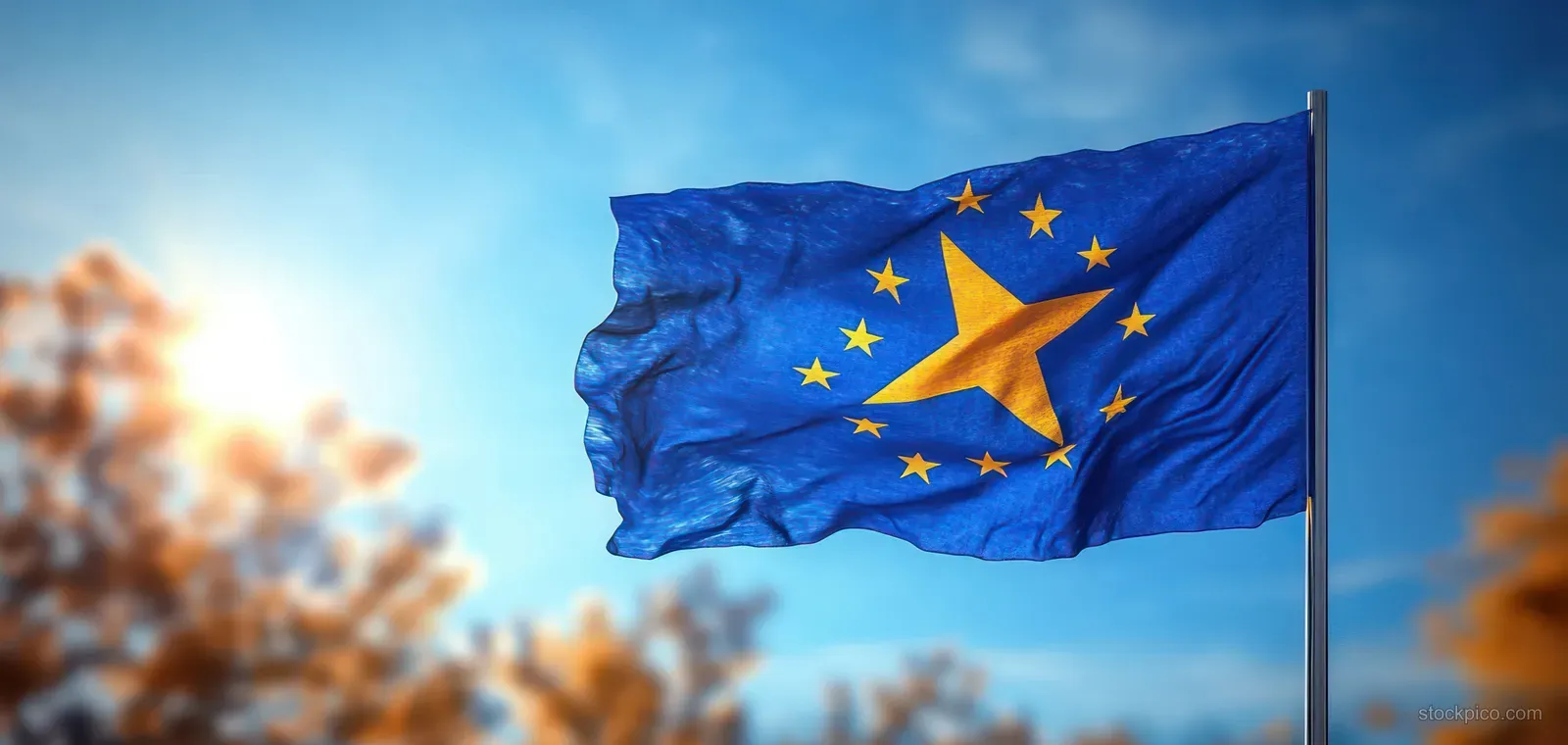 Kosovo flag waves on a pole with yellow stars against a clear blue sky.