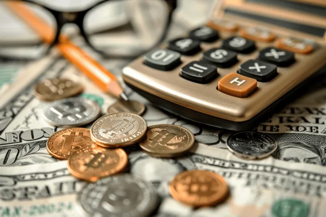 Calculator beside coins on tax documents with orange pen for 2024 planning
