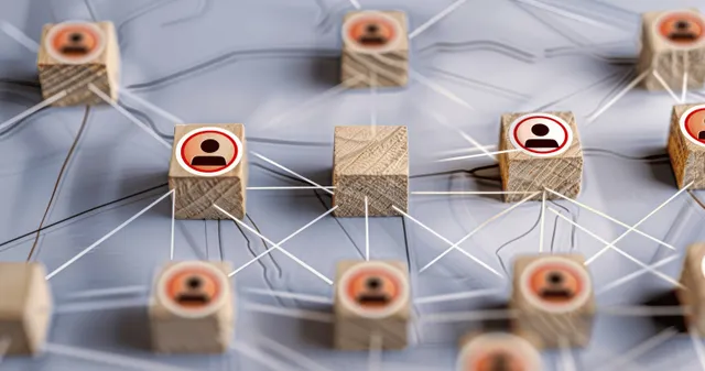 Wooden blocks with human icons linked by white lines forming a business network