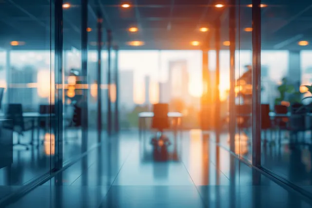 Sunlit glass-walled conference corridor with blurred office seating and glowing bokeh lights