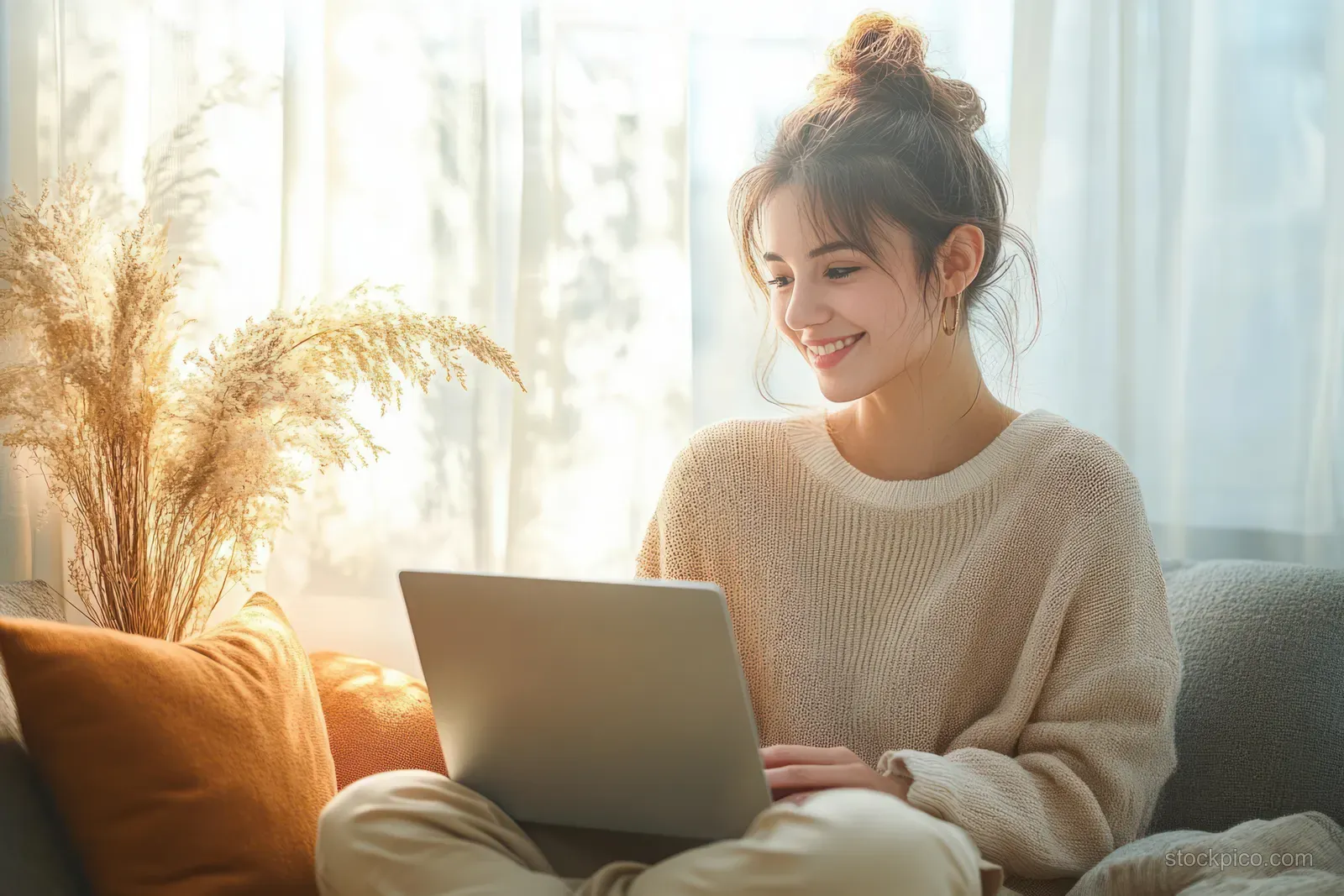 Smiling woman using a laptop in a sunlit minimalist home office.