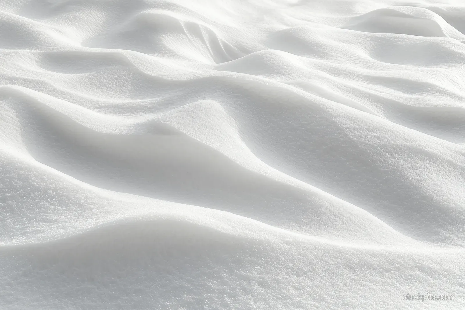 Smooth snow surface with gentle ripples and soft shadows across an untouched winter landscape.