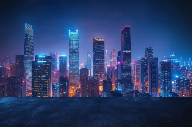 Bangkok skyline at night with glowing skyscrapers and colorful lights reflected on an empty asphalt road.