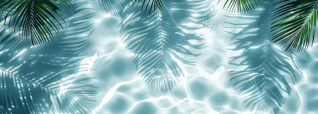 Abstract palm leaf shadows overlay rippled blue water and white sand, creating a tropical beach background with clean copy space.
