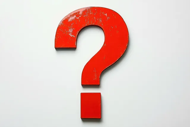 Worn red question mark on white surface with distressed texture and bold cutout shape