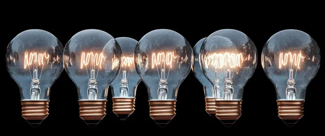 Glowing light bulbs in a row with motivational words etched inside