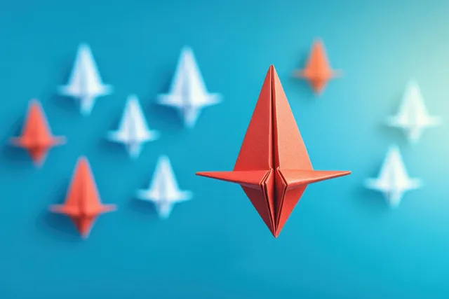 A red origami paper plane stands out among white planes on a blue background, symbolizing leadership and competition.