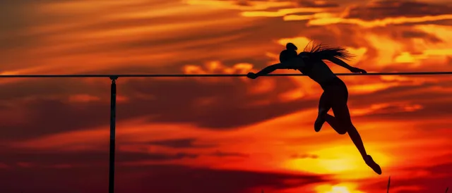 Cuban high jumper silhouette clearing the bar on a stadium track at vivid sunset