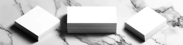 Stacked business cards on marble desk with soft shadows and blank copy space