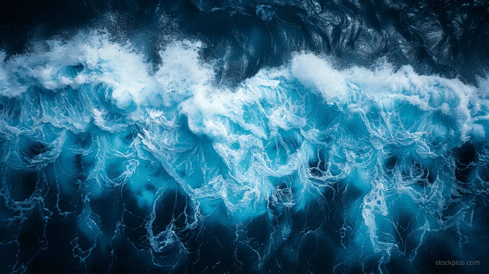 Top-down view of ocean waves with white foam over deep blue water.