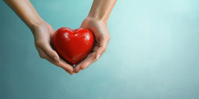 Hands cradling a red heart symbolizing health care support and charity donation