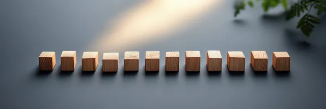 Wooden domino blocks in a row with one block placed to stop the falling chain in a gray minimalist setting.