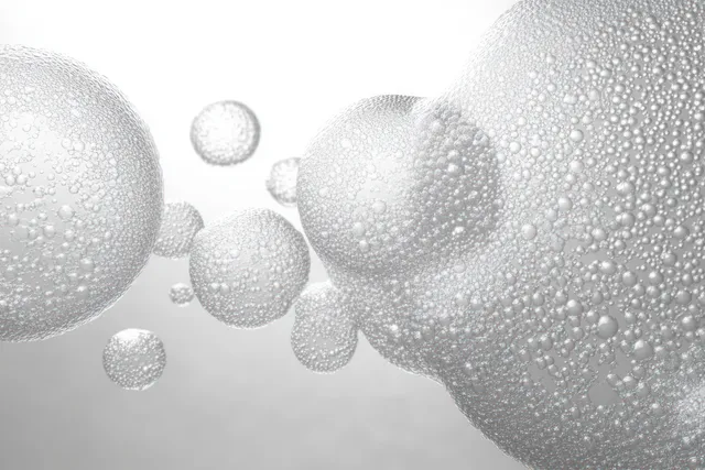Macro close-up of transparent bubbles coated in tiny droplets against a bright white backdrop