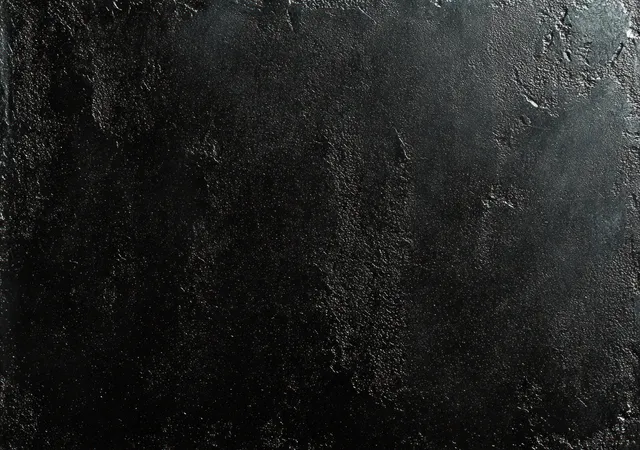 Macro close-up of rough black wall texture with uneven gritty stone-like grain