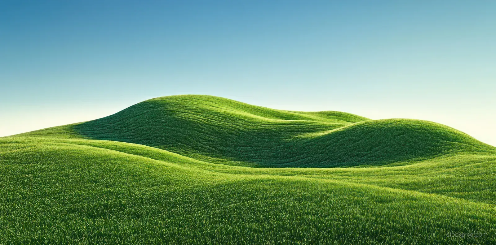 Rolling green hills rise beneath a clear blue sky with smooth grassy contours and soft shadows.