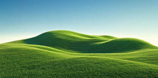 Rolling green hills rise beneath a clear blue sky with smooth grassy contours and soft shadows.