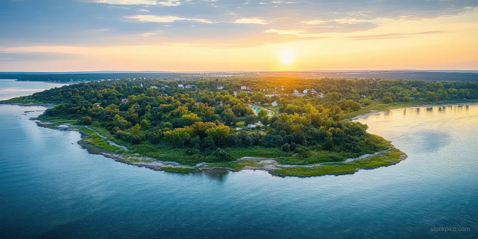 Drone aerial view of Funtana Croatia coastline with green shoreline and glowing sunset sky over calm bay water.