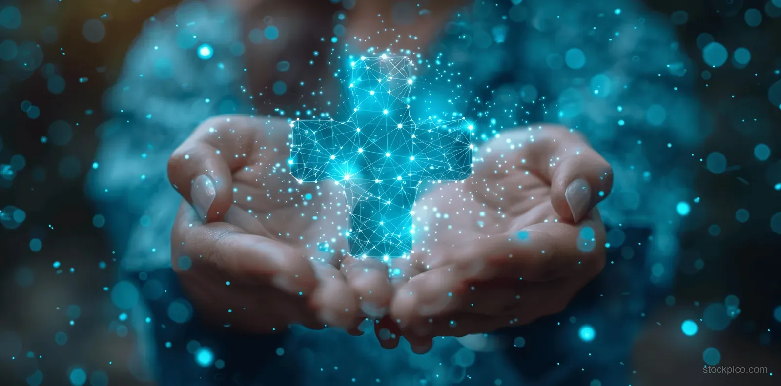 Hands hold a glowing medical cross symbol over a blurred hospital background with blue digital light particles.